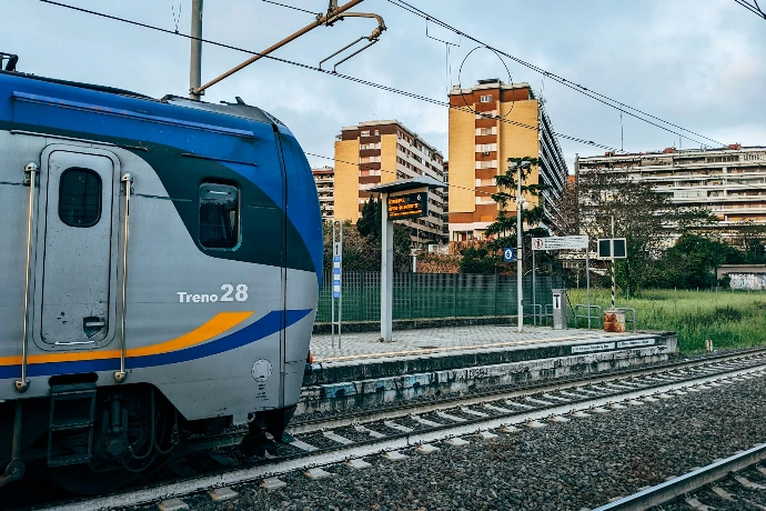 a blue and silver train traveling past tall buildings
